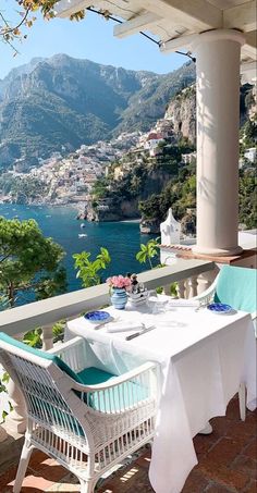 an outdoor dining area overlooking the water and mountains with white table cloths on it