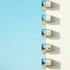 an apartment building with balconies and balcony railings in front of a blue sky