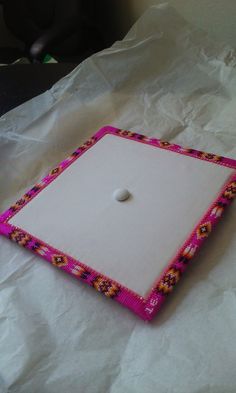 a pink and white square shaped object sitting on top of a sheet of paper