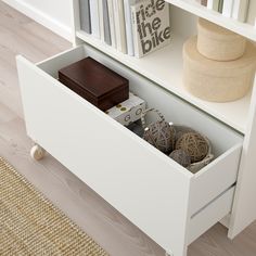 a white book shelf filled with books next to a rug and a wooden table top