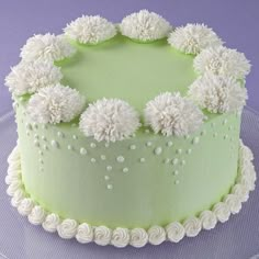 a green cake with white frosting and pom - poms on the top