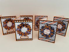 four cards with orange and purple designs on them, one has a wreath in the middle