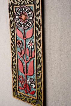 an ornately decorated wall hanging on the side of a building with flowers and leaves