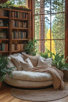 a living room with bookshelves, plants and a round couch in front of a window