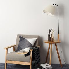 a living room with a chair, lamp and books on the floor next to it