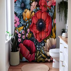 a bathroom with a floral shower curtain and rug in front of the toilet, next to a potted plant