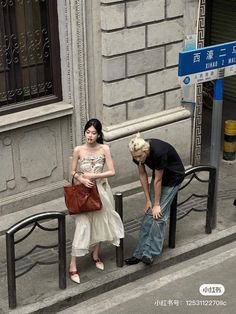 a man and woman standing on the side of a street