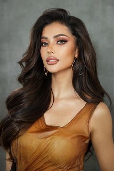 a woman with long brown hair wearing gold dress