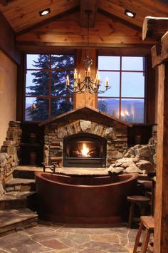 a fireplace in the middle of a room with stone steps and a large bathtub