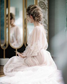 a woman sitting on the floor in front of a mirror looking at her cell phone