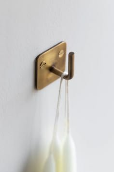 two white vases are hanging on the wall and one is holding a brass hook