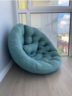 a blue chair sitting on top of a wooden floor next to a large glass window