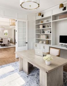 a desk with a laptop on top of it in front of a bookcase and bookshelf