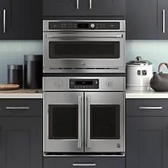 a kitchen with black cabinets and stainless steel appliances, including two ovens and one microwave