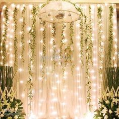 wedding stage decoration with white flowers and greenery hanging from the ceiling, surrounded by fairy lights