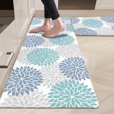 a person standing on top of a blue and white flowered rug in a kitchen