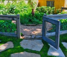 two wooden frames sitting in the grass next to each other on top of a stone walkway