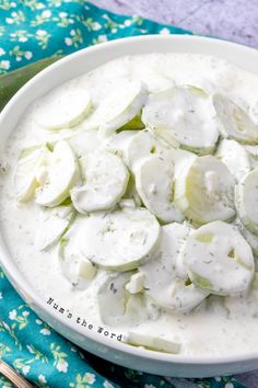 a white bowl filled with cucumbers on top of a blue and green cloth