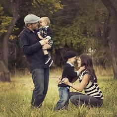 a man, woman and child are sitting in the grass with their hands around each other