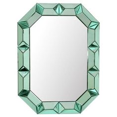 a mirror that is sitting on top of a white wall and has green glass in the middle