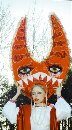 a woman is dressed up as a fox with her head in the shape of a mask