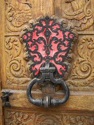 an ornate wooden door with metal handle and decorative design on the front part of it