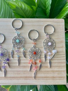 four keychains with different designs on them sitting on a wooden board next to some plants