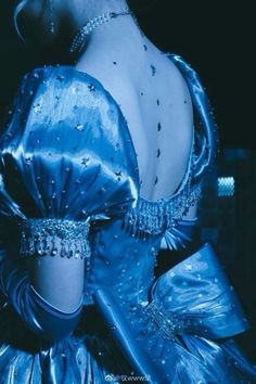 the back of a woman's blue dress with pearls on her head and shoulders