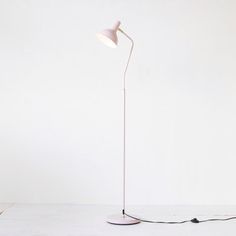 a white floor lamp sitting on top of a table next to a black light bulb