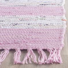 a pink and white rug with fringes on the floor