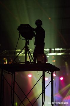 a man standing on top of a stage holding a projector in his right hand