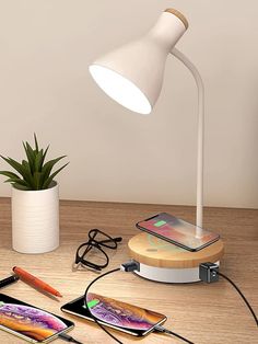 an iphone charging on a table next to a plant and some other items that are plugged into the charger