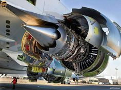 an airplane engine sitting on top of an airport tarmac with people standing around it