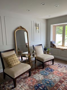 a living room with two chairs and a large mirror on the wall next to a window