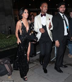 two people dressed in black and white are walking down the street with one person wearing a tuxedo