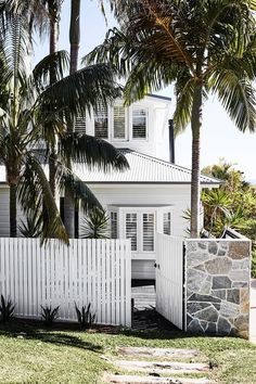 a white house with palm trees in the front yard and steps leading up to it