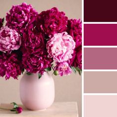 a white vase filled with pink flowers on top of a wooden table next to color swatches