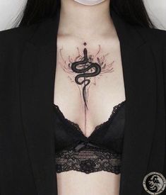 a woman wearing a black bra with a snake tattoo on her chest and under breast