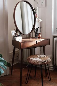 a wooden vanity table with a mirror and stool in front of it on top of a hard wood floor