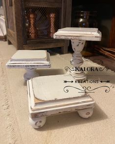 an old white table with two small stools on it's legs and one sitting on the floor