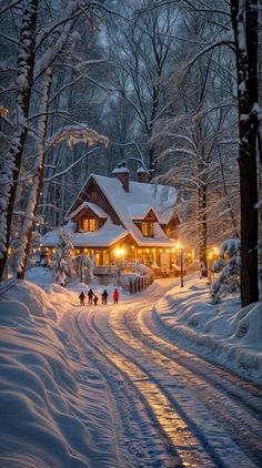 people walking down a snowy road in front of a house with lights on at night