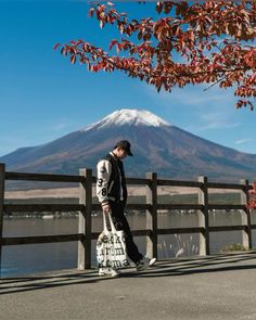 a man walking down the street with a bag in his hand and a mountain in the background