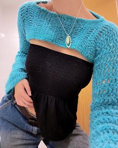 a woman wearing a blue sweater and black top is holding her belly in front of the camera