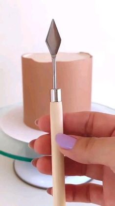 a person holding a small toothbrush in front of a white cup and saucer