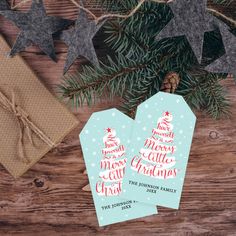 two christmas gift tags sitting on top of a wooden table