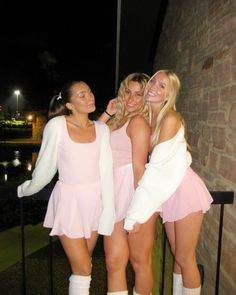 three beautiful young women standing next to each other in short skirts and knee high socks