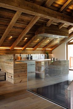 an open kitchen with wooden walls and flooring in a loft style home, along with exposed wood beams on the ceiling