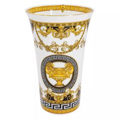 a white vase with gold trimmings and designs on the outside, sitting in front of a white background