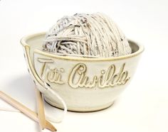 cream colored yarn bowl personalized with the name Titi Awilda has three holes for needles and a cutout slit for yarn to glide through with a ball of variegated yarn in it and pair of large wooden knitting needles Knit Gifts, Ceramic Yarn Bowl, Yarn Bowls, Yellow Crochet, Yarn Holder, Crafter Gift, Knitting Bag, Painting Accessories, Butter Yellow