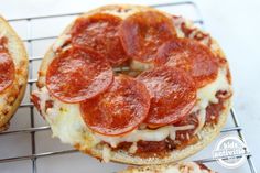 two pepperoni pizzas sitting on top of a cooling rack